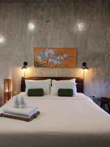 um quarto com uma grande cama branca e 2 toalhas em Arun Rawee อรุณ รวี em Chiang Mai