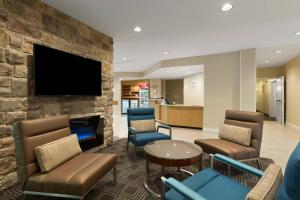 a waiting room with chairs and a tv on a stone wall at TownePlace Suites Boone in Boone