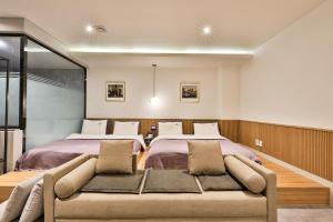 um quarto com uma cama grande e um sofá em Brown Dot Hotel Jeonggwan em Busan