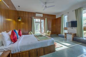 1 dormitorio con 1 cama grande con almohadas rojas y azules en The Cloyster Resort and Spa en Rāmnagar