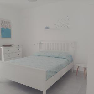 una camera bianca con letto e comodino di Casa Vacanze Pesce Palla a Villaggio Azzurro