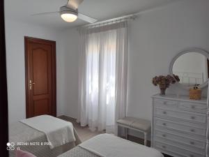 a white bedroom with a dresser and a mirror at Casa La Loma en Archidona in Málaga