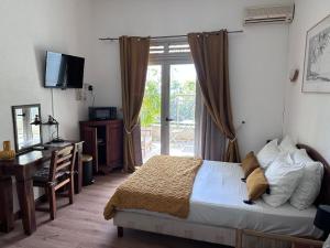 a bedroom with a bed and a desk and a television at Hôtel Résidence Le Phoenix in Saint-Pierre +42 photos