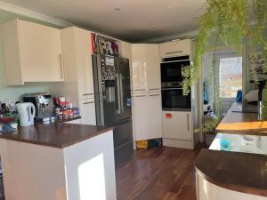 a kitchen with white cabinets and a black refrigerator at Bright, comfy and peaceful house in Inverkeithing