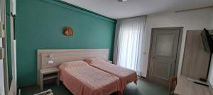 - une chambre avec un lit et un mur vert dans l'établissement Hotel Splendor, à Grado