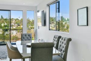 Luxury retreat with rooftop, hot tub & views في لوس أنجلوس: غرفة طعام مع طاولة وكراسي ونوافذ