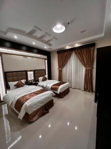 a bedroom with two beds and a large window at أسطورة حراء للشقق المخدومة in Jeddah