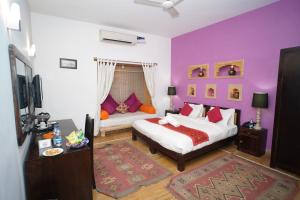 ein lila Schlafzimmer mit einem Bett und einem Sofa in der Unterkunft Hotel Jaisan Haveli in Jaisalmer