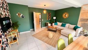un soggiorno con divano bianco e pareti verdi di BeCosy appartement 2 chambres et jardin 6 pers a Mons