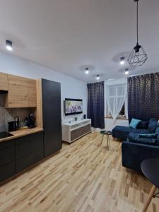 MAGIC HOME Apartamenty في رودا شلاسكا: غرفة معيشة مع أريكة زرقاء ومطبخ