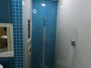 een blauwe betegelde douche met een glazen deur in de badkamer bij ID Hotel in Passo Fundo