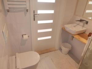 a white bathroom with a toilet and a sink at Motyl Apartamenty Studio in Bytom