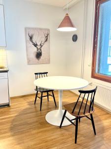 une table et des chaises blanches dans une cuisine avec un tableau de cerfs dans l'établissement Seaside Apartment, à Helsinki