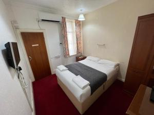 um pequeno quarto com uma cama e uma televisão em Bonair Hotel em Paignton