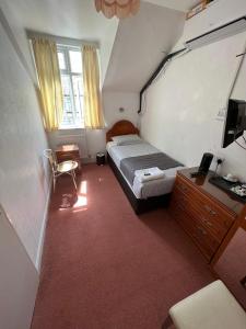 um quarto com uma cama, uma secretária e uma televisão em Bonair Hotel em Paignton