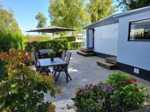 un patio con una mesa, una sombrilla y algunas flores en Chalet Renswouw en Renswoude