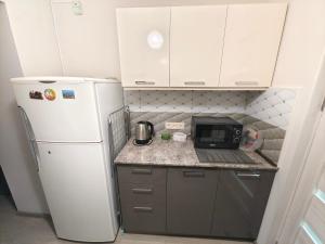 uma pequena cozinha com frigorífico e micro-ondas em Cosy Home em Guiumri