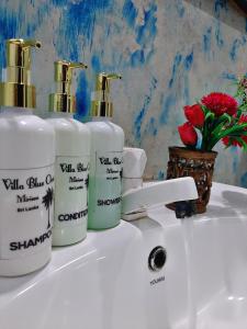 a white sink with three bottles of soap and a flower at Villa Blue Ocean in Mirissa