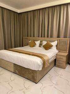 sypialnia z dużym łóżkiem z białą pościelą i poduszkami w obiekcie أبراج الجزيرة w mieście Al-Hufuf