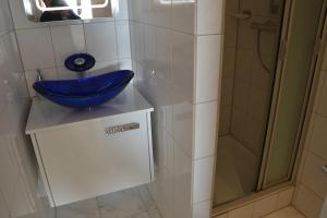 y baño con lavabo azul y ducha. en Meerblick FeWo Nr A-107 en Sierksdorf