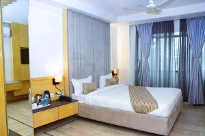 1 dormitorio con 1 cama blanca grande y cortinas azules en CRYTSAL RESIDENCY, en Ranchi