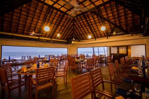 un comedor con mesas, sillas y ventanas en MGM Beach Resorts East Coast Road, en Chennai