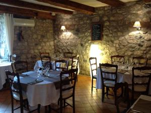 uma sala de jantar com mesas e cadeiras e uma parede de pedra em L'Auberge De Montpezat em Montpezat-sous-Bauzon