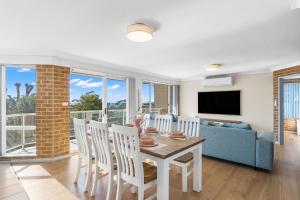 a living room with a table and chairs and a couch at Bella Vista: Ocean views a short stroll to beach. in Mollymook