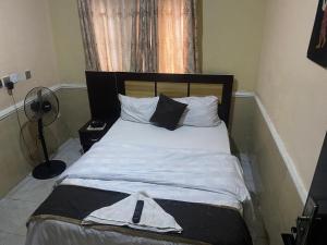 ein Bett mit weißer Bettwäsche und Kissen in einem Schlafzimmer in der Unterkunft Belmorris Hotel in Ilorin