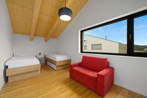 a bedroom with a red chair and a window at Vánice pod Klínovcem in Loučná pod Klínovcem