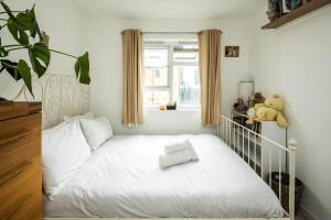 a white bed in a room with a window at 2BD Stylish Home w/t Grand Piano Central London in London