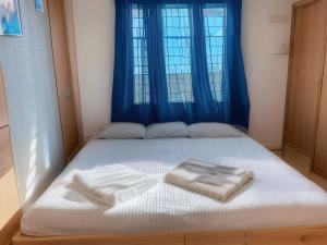 uma cama com duas toalhas em frente a uma janela em RAHEE GUEST HOUSE em Guwahati