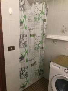 ein Badezimmer mit einem Duschvorhang und einer Waschmaschine in der Unterkunft La casa dei nonni in Talavà
