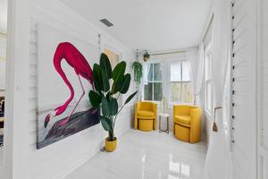 a living room with a pink flamingo painting and yellow chairs at Coco's Cozy Cabana - Hot Tub Walk to Downtown in Saint Augustine +31 photos