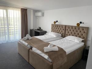 duas camas num quarto de hotel com toalhas em Hotel Maya em Horezu