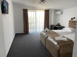 um quarto de hotel com uma cama grande e uma janela em Hotel Maya em Horezu