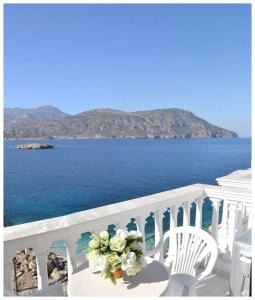 a white balcony with a table and chairs and the ocean at Dolphin Hotel Apartments in Karpathos Town