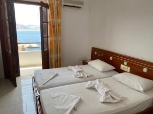 una camera con due letti con lenzuola bianche e una finestra di Dolphin Hotel Apartments a Karpathos