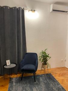 een woonkamer met een blauwe stoel en een plant bij Liman Rooms and Apartments in Mostar