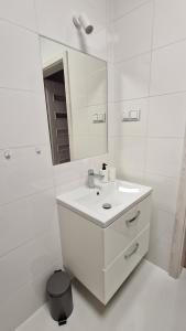 La salle de bains blanche est pourvue d'un lavabo et d'un miroir. dans l'établissement Apartament Przy Dworcu (centrum), à Tarnowskie Góry