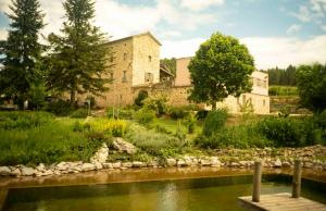 a stone house with a river in front of it at Mas Héritage, 1455 route de Balbiac in Rosières
