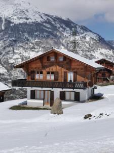 una casa en la nieve con una montaña en CHALET HÜTTLE - authentisch, ruhig, mitten im grün en Grächen
