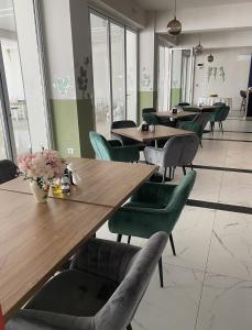 a restaurant with wooden tables and green chairs at Hotel Maya in Horezu