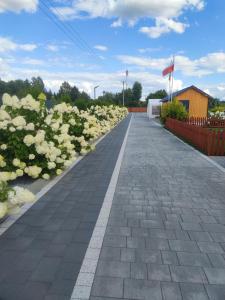 einen steinernen Gehweg mit weißen Blumen und einer Flagge in der Unterkunft MIODOWA SADYBA Domki całoroczne in Ligota Zamecka