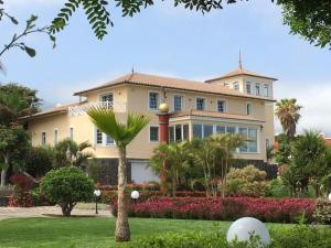 a large house with a palm tree in front of it at Finca El Cardinal - Atemberaubende Luxusvilla in Icod de los Vinos