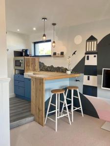 a kitchen with a island with stools and a lighthouse at Mevagissey Boutique Flatlet with sea and countryside views in Mevagissey