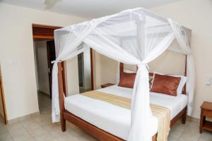 1 dormitorio con 1 cama con dosel en Galu Gardens Diani Beach ,Coastal Apartments by Nest & Nomad en Kwale