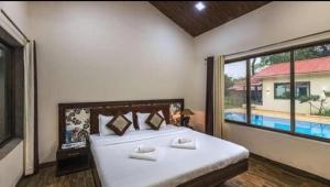 a bedroom with a large bed and a large window at Tiara Resort Mandwa in Alibaug
