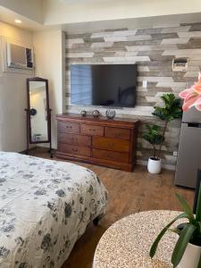 une chambre avec un lit et une commode avec une télévision dans l'établissement Seaview Amani Grand Resort Residences 3-5mins from airport, à Mactan