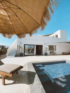 a house with a swimming pool and an umbrella at Villa Koa - Riders Surf n Bike in El Roque